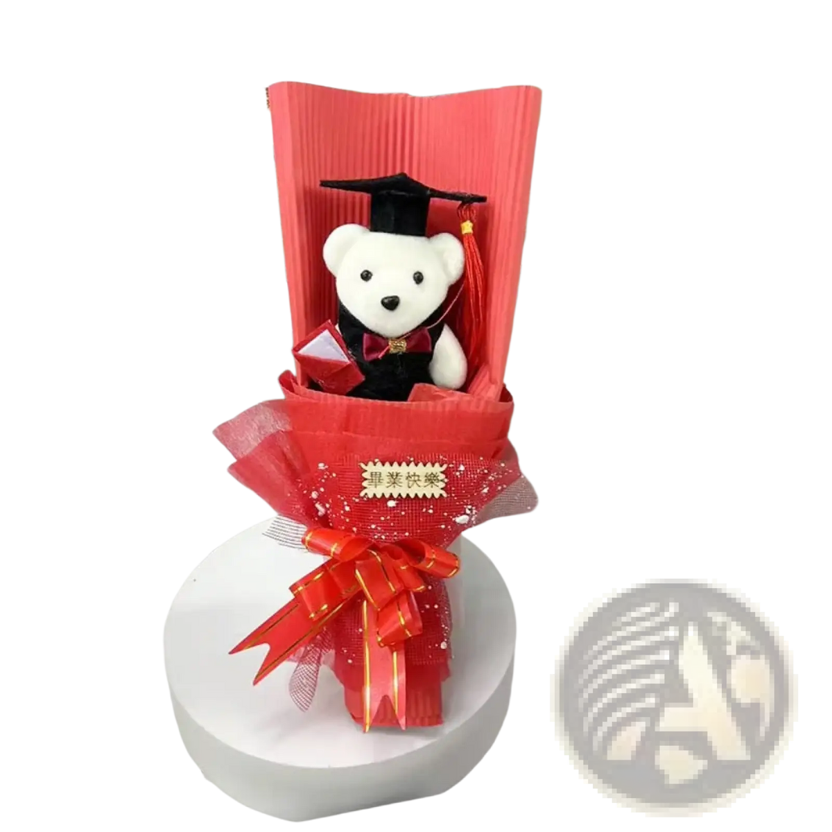 A plush white teddy bear wearing a black graduation cap and red bow tie in a red bouquet with glitter accents