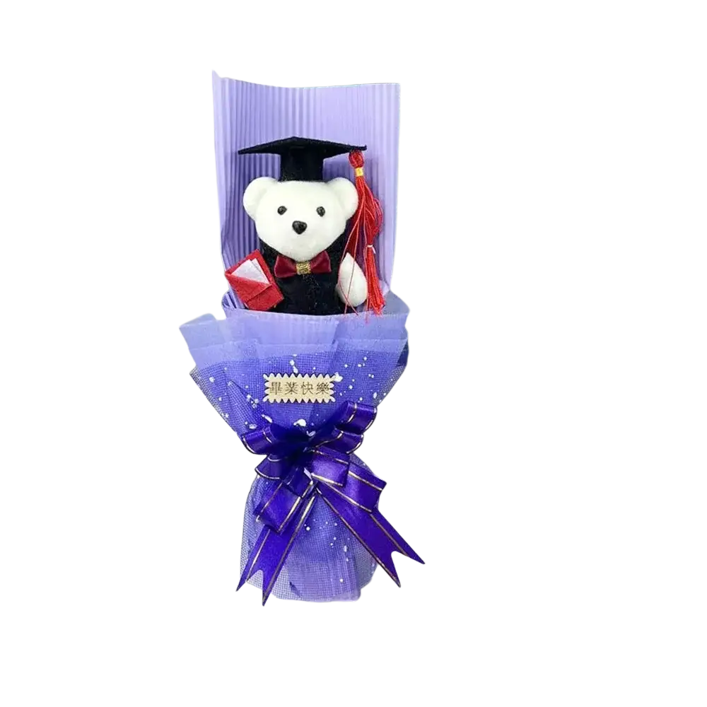 A plush white teddy bear dressed in a black graduation gown with red sash and cap in a graduation bear bouquet gift