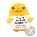A yellow crocheted duck with black bead eyes and orange beak holding a white sign saying youre ducking awesome graduation gift 2025
