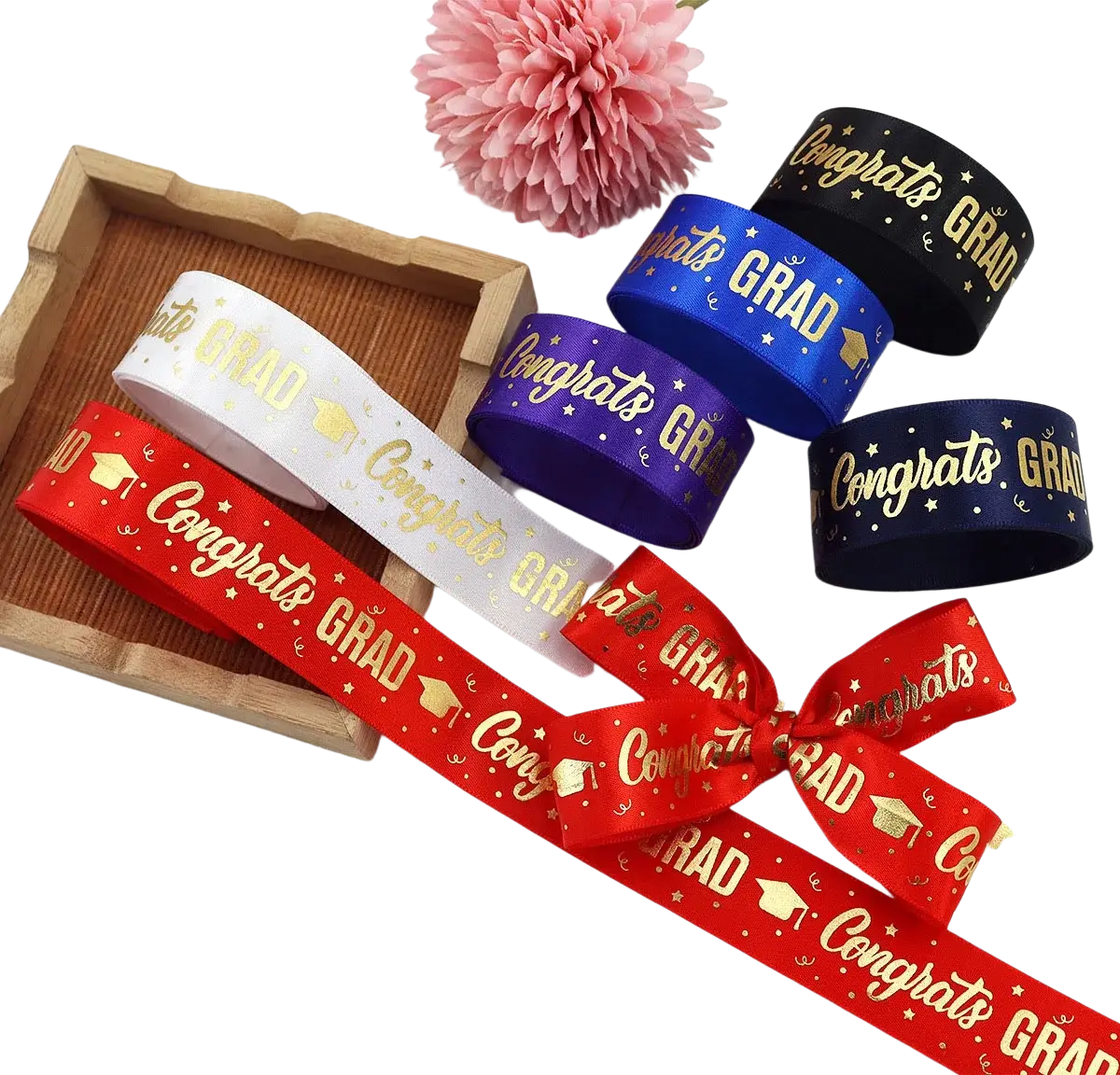 Red satin graduation gift wrapping ribbon with gold congrats grad text and graduation cap motifs tied into a bow