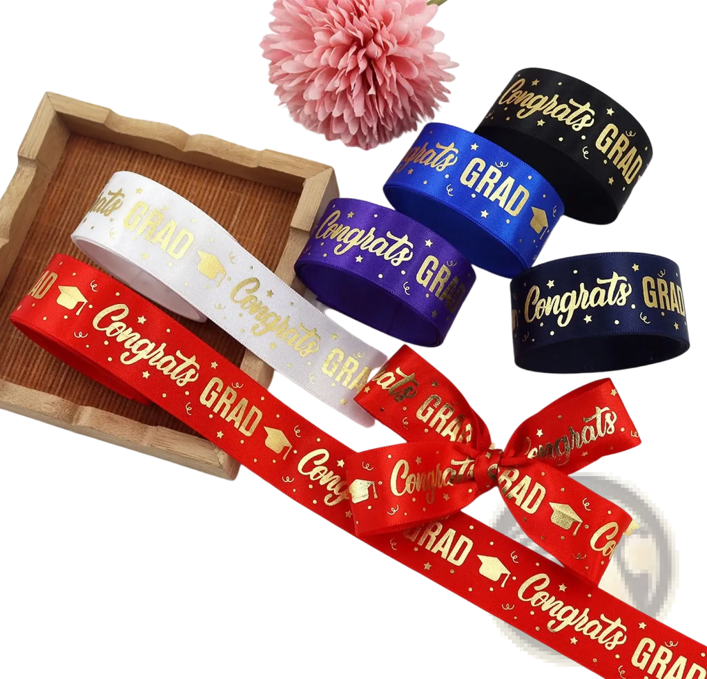 Red satin graduation gift wrapping ribbon with gold congrats grad text and graduation cap motifs tied into a bow