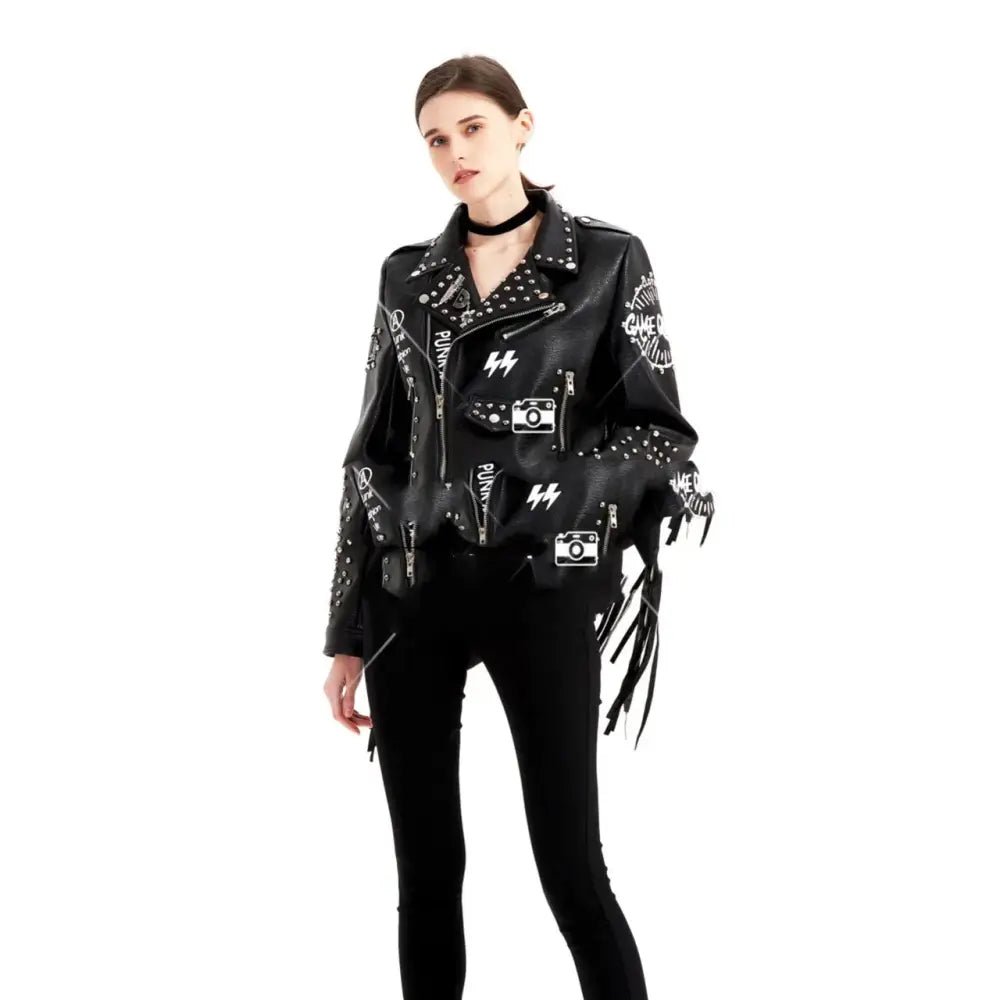 Black leather biker jacket for women with white studded patches, camera and lightning bolt graphics, and fringed sleeves