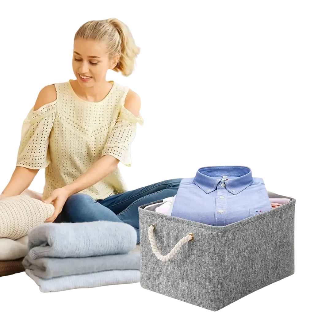 Gray foldable woven fabric storage basket with white rope handles containing a folded blue button-down shirt