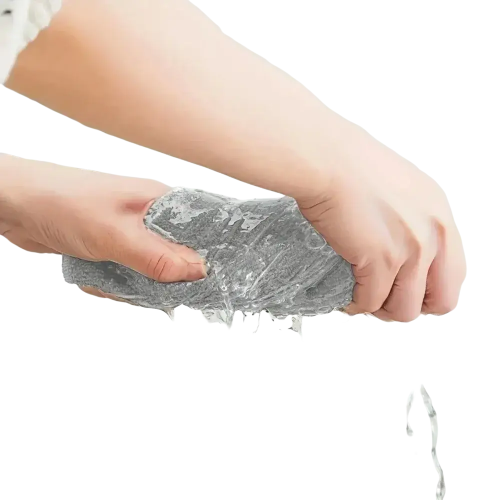 Gray microfiber cleaning cloth being squeezed under running water showing its textured absorbent material