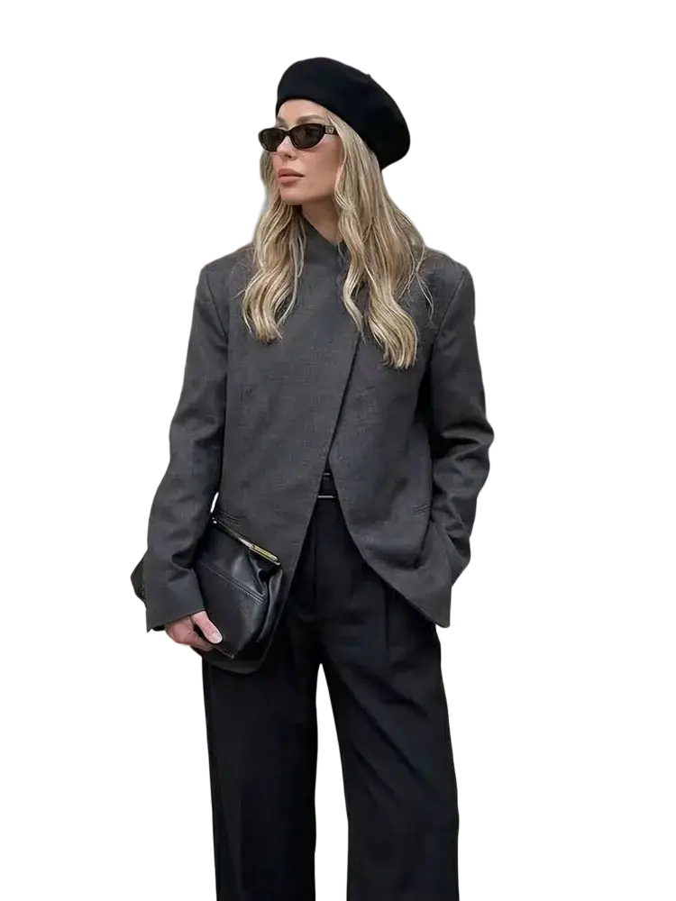 Black leather crossbody bag with gold zipper pull complementing a gray plaid oversized blazer
