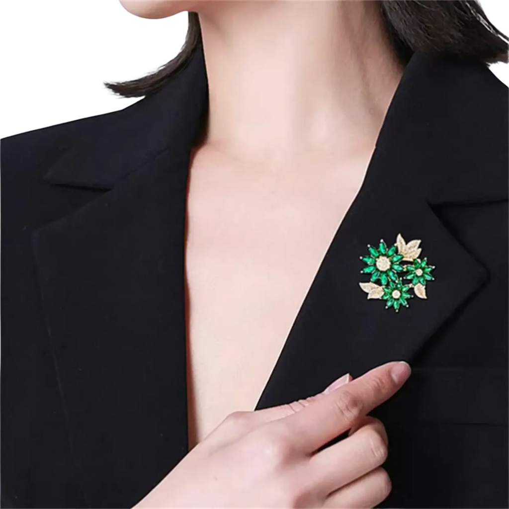 A sparkling green and gold floral rhinestone brooch pin elegantly pinned to a black blazer lapel