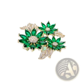 A green floral rhinestone brooch pin sparkling with green and gold tones featuring emerald-cut crystals and pave-set diamonds