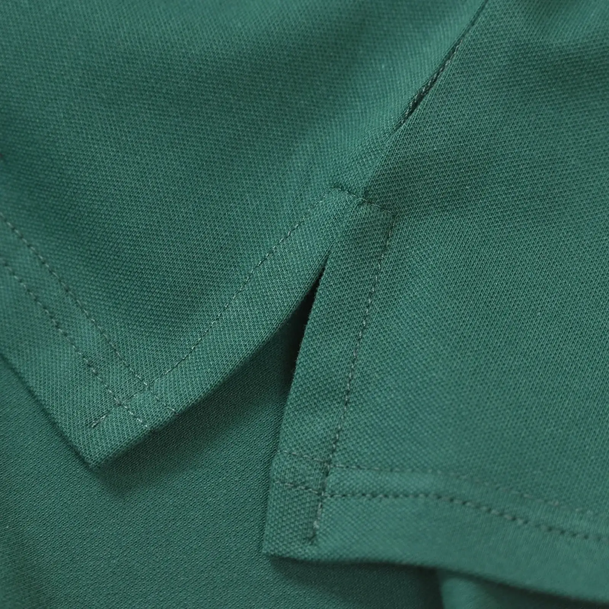 Dark green polo shirt collar with neat stitching and subtle textured weave in green golf bear embroidered design