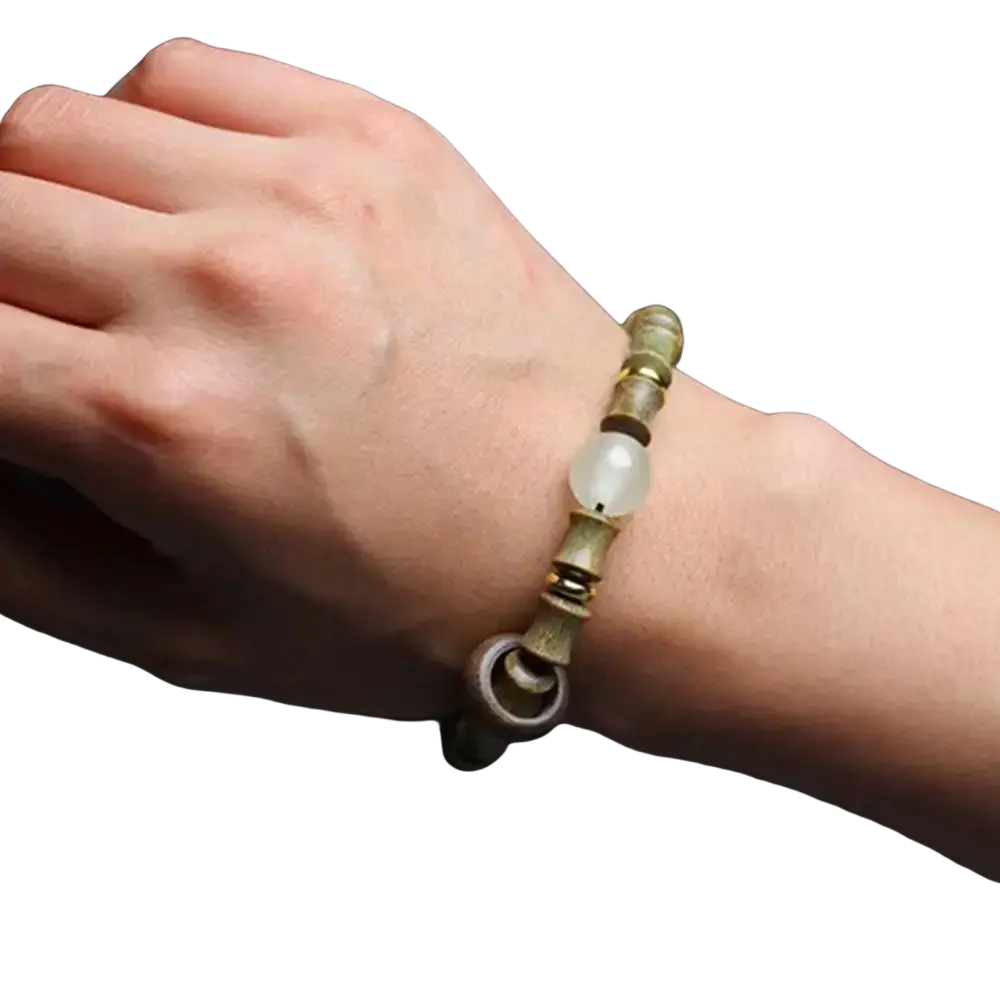 Delicate green sandalwood hand bracelet with a central translucent bead and metallic green and gold detailed beads