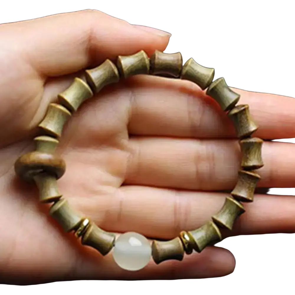 A hand holds a green sandalwood hand bracelet featuring bamboo beads and one translucent white jade sphere accent