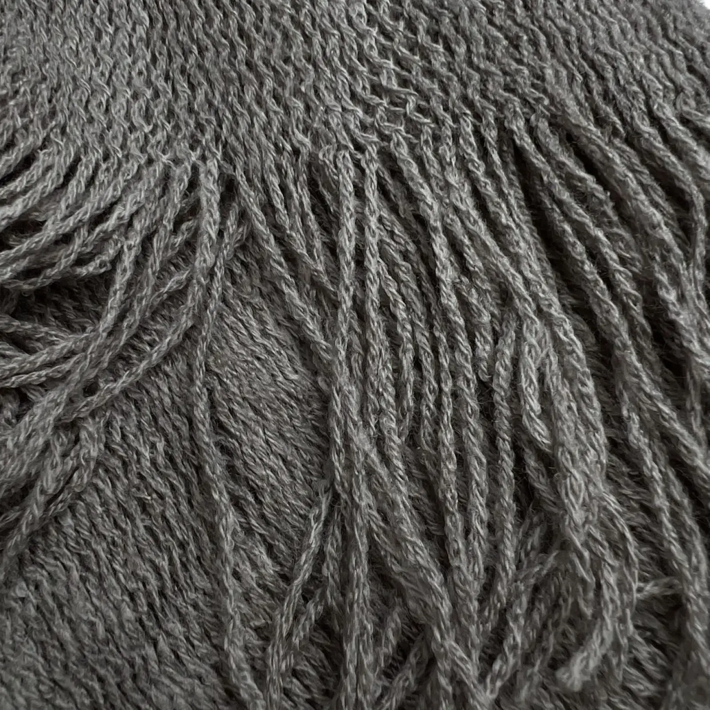 A soft textured gray knitted grey acrylic skinny scarf with fringe lightweight winter accessory