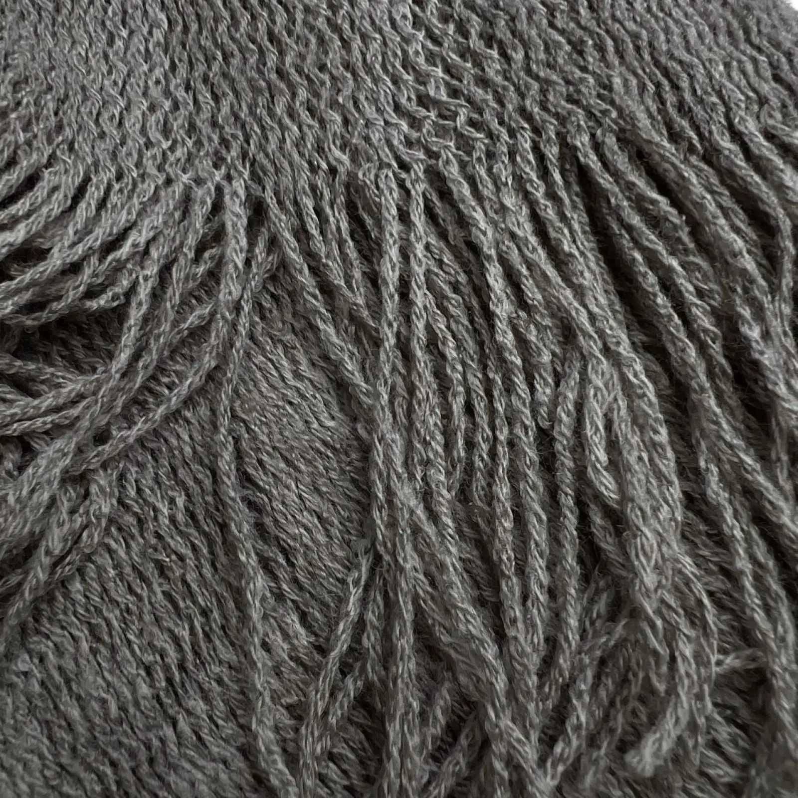 A soft textured gray knitted grey acrylic skinny scarf with fringe lightweight winter accessory
