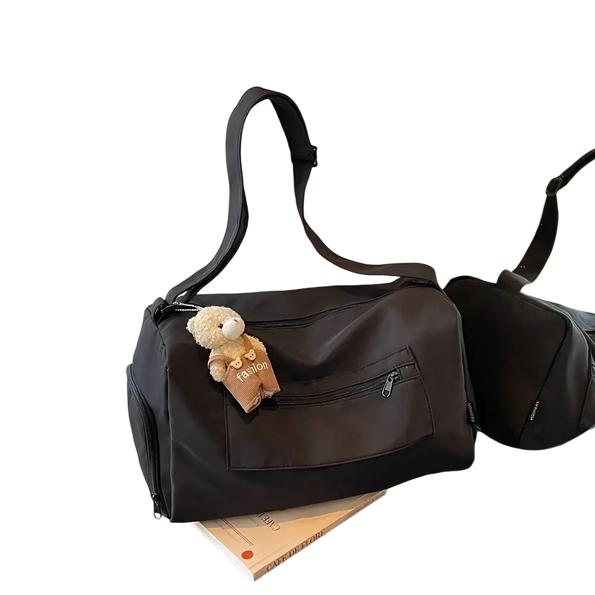 Black nylon gym duffle bag with detachable shoulder strap and beige teddy bear charm on front zipper pull