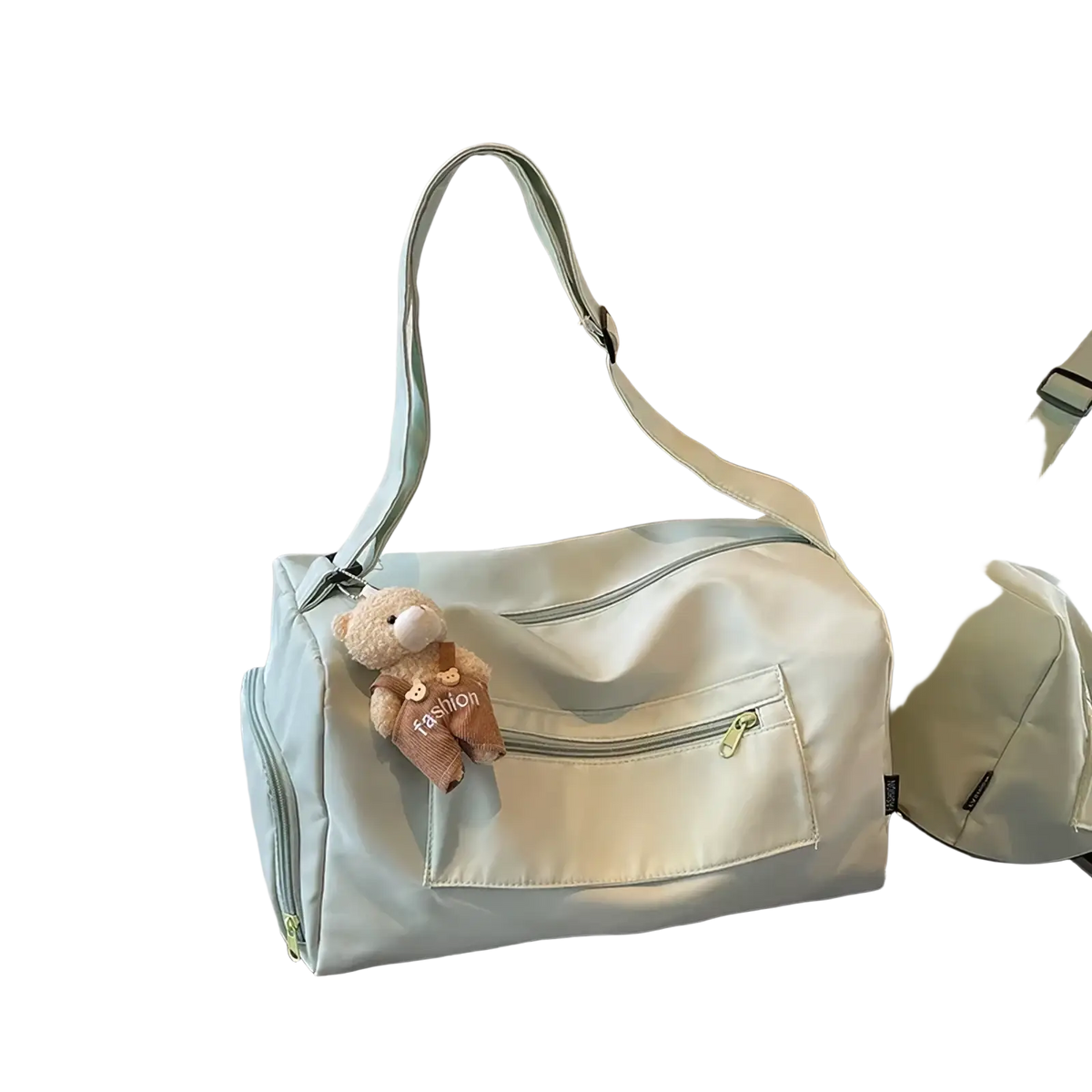 A soft mint green gym duffle bag with adjustable strap front zip pocket and beige teddy bear charm for travel use