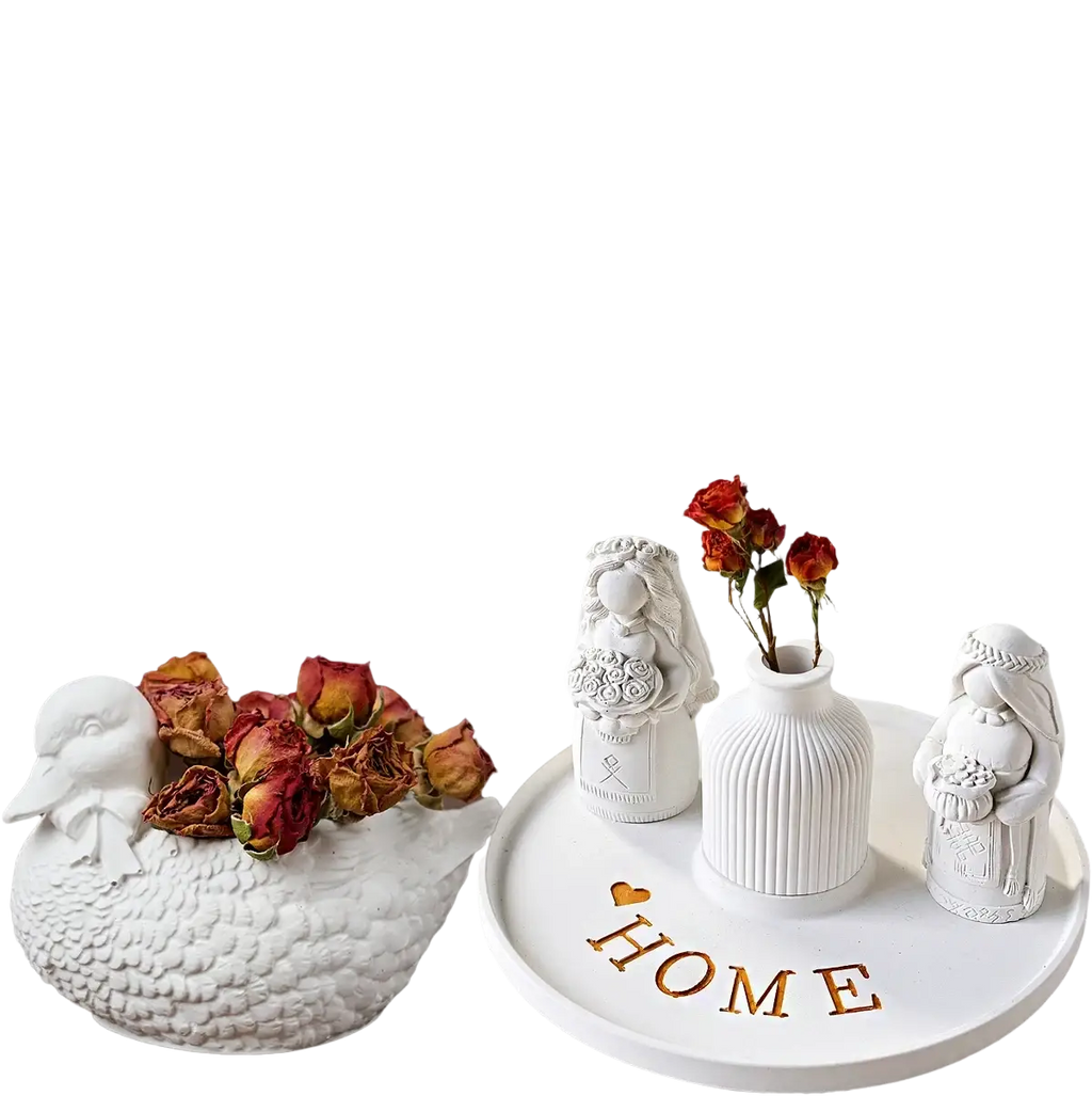 White ceramic gypsum casting powder figures featuring detailed bridal designs and ribbed vase with dried roses on home tray
