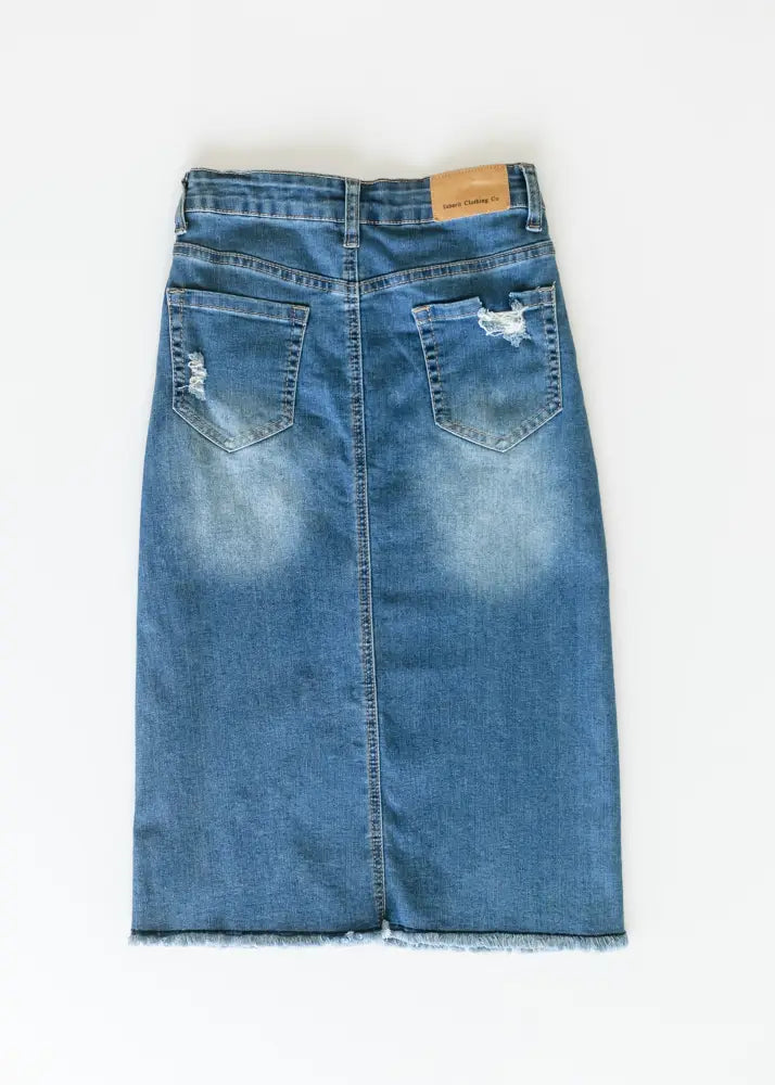 Hadley high rise distressed denim midi skirt in medium blue wash with frayed hem and distressed back pockets shown from back