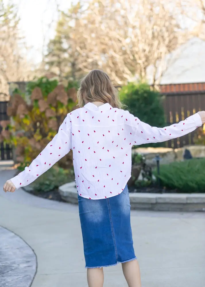 White long-sleeved blouse with red leaf patterns paired with hadley high rise distressed denim midi skirt front view