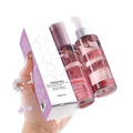 A hand holds a 100ml hair care essential oil bottle with pink liquid and purple spray beside minimalist cocoon packaging