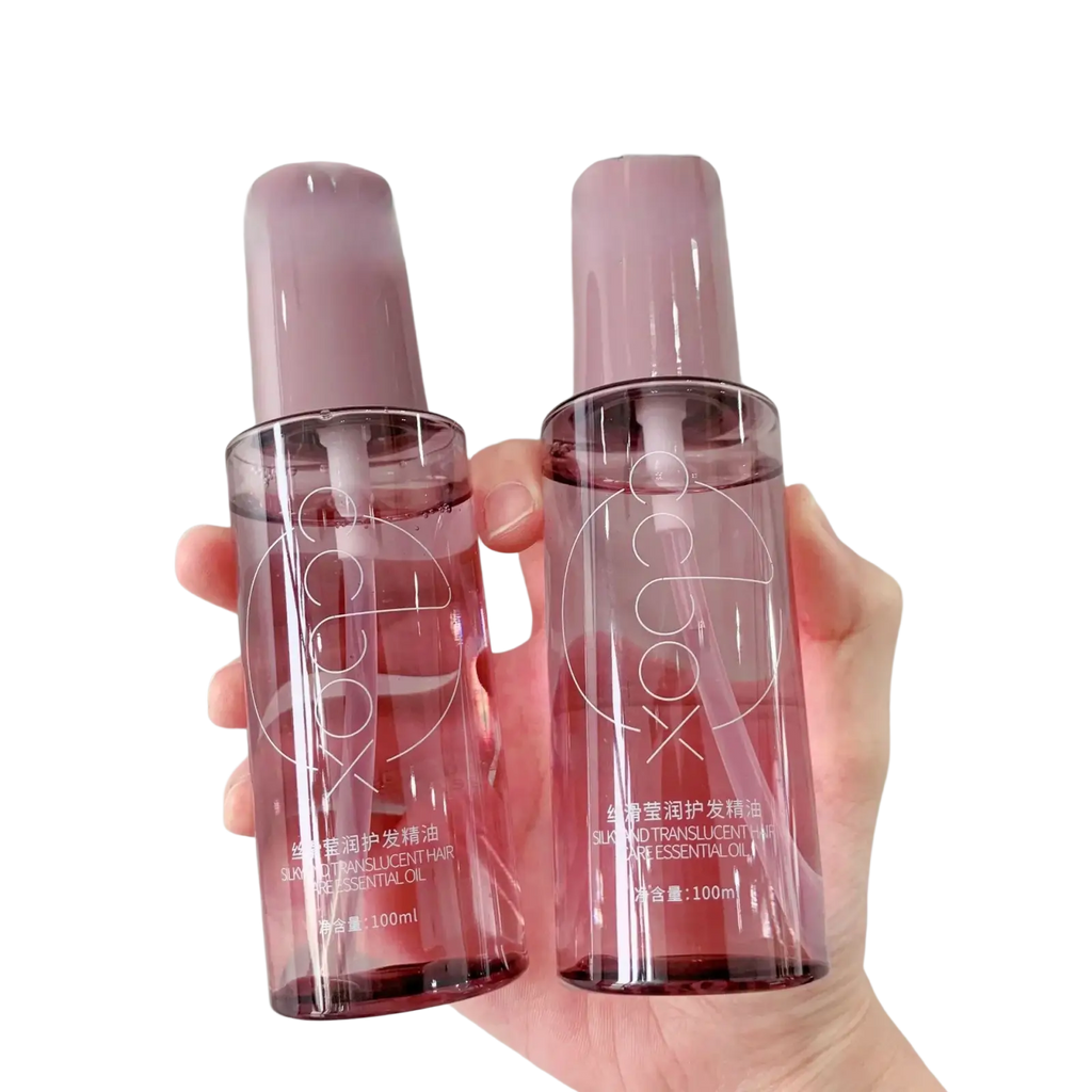 Two translucent pink glass bottles of 100ml hair care essential oil with purple caps for dry hair care essential use