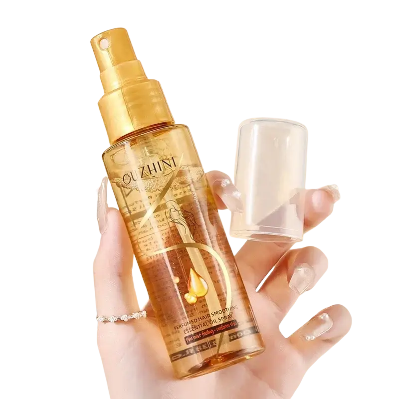 Golden hair care essential oil spray of ouzhini with transparent amber body and gold accents for luster and repair