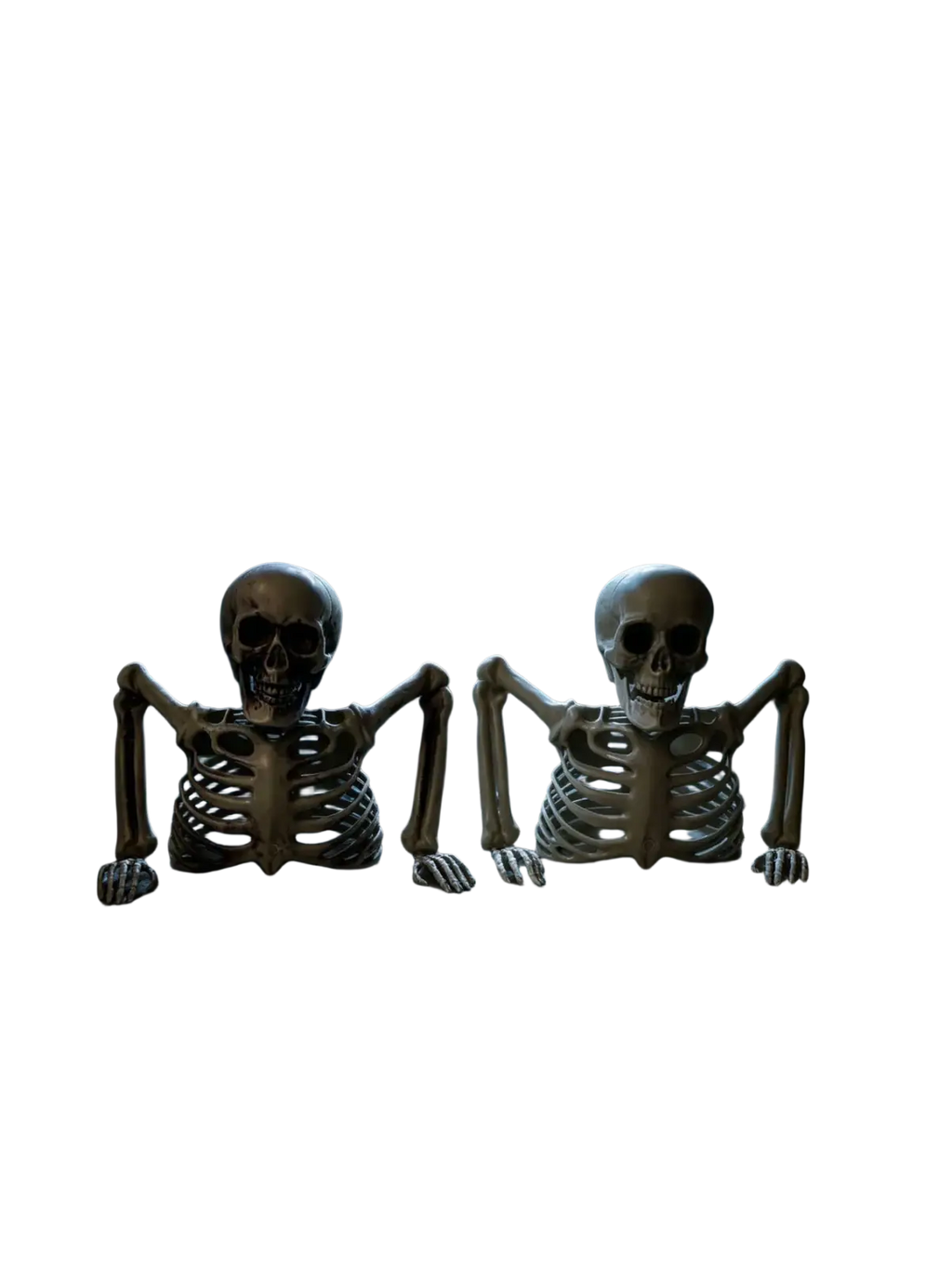 Two beige plastic halloween half skeleton decorations with articulated limbs on stone windowsill for terrifying scenes