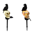 A halloween outdoor light skeleton crow solar garden stake with black crow on white skull illuminated by orange glow