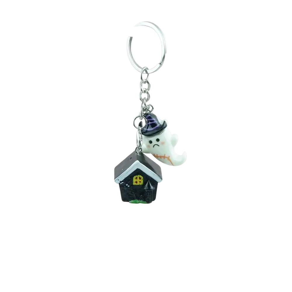 A handmade resin halloween pumpkin keychain featuring a white ghost with a purple hat above a black haunted house