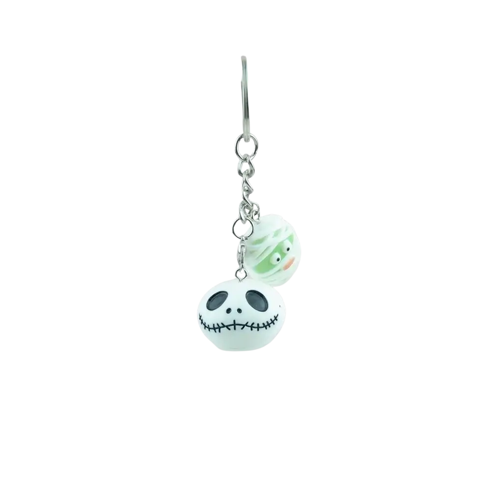 A pale green and white handmade resin halloween pumpkin keychain featuring jack skellington and mummy heads