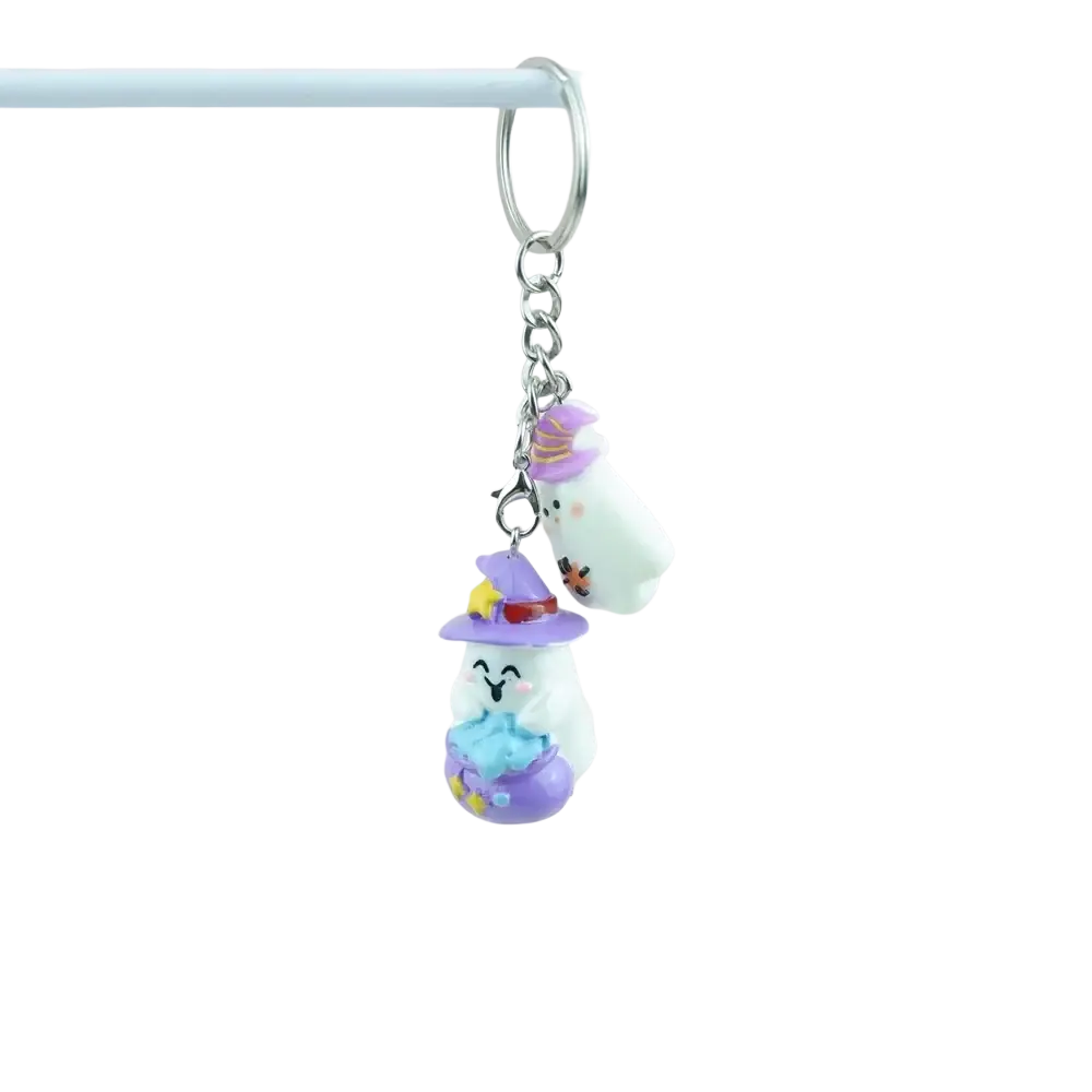 A handmade resin halloween pumpkin keychain featuring two white ghost figurines with purple witch hats and colorful details