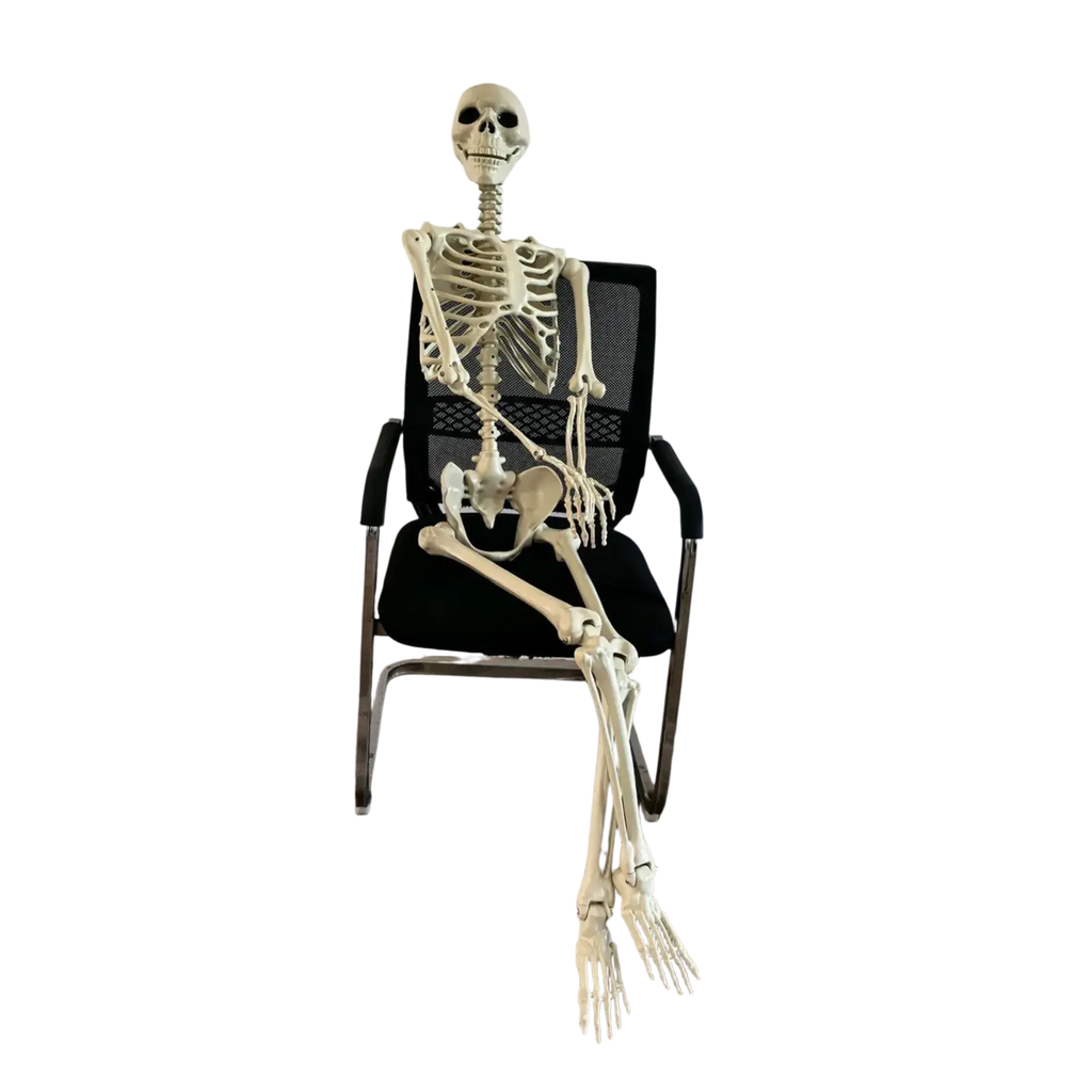 A beige plastic halloween skeleton posable garden decor seated in a black mesh office chair for haunted house use