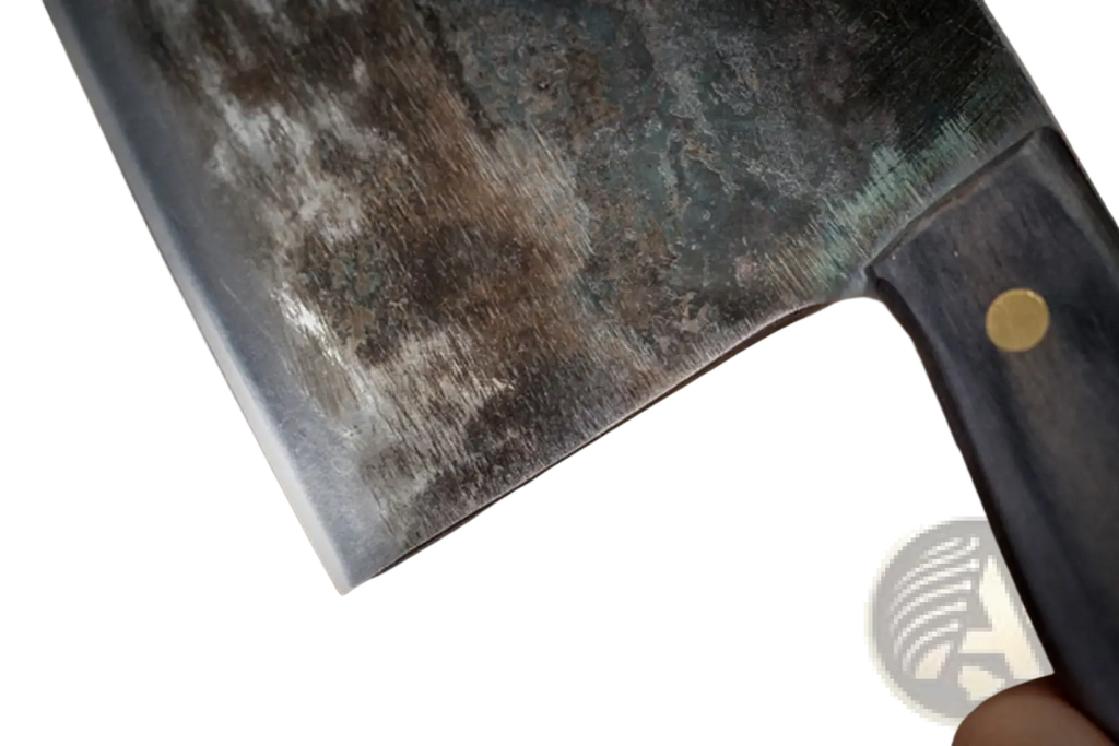 A well-worn dark gray hand-forged high carbon stainless steel meat cleaver with black handle and gold rivets