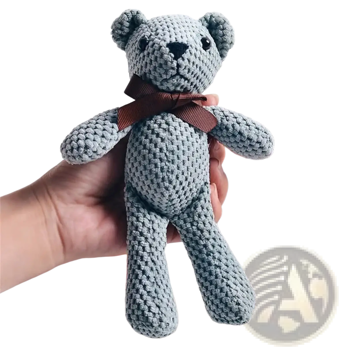 Handmade crochet teddy bear plush toy in soft light gray with black button eyes and brown ribbon bow around neck