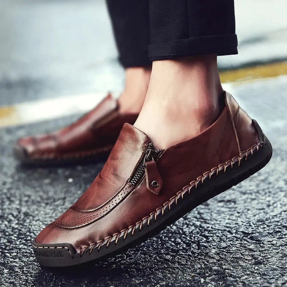 Men’s handcrafted brown leather slip-on loafer dress shoe with zipper closure and decorative stitching along sole