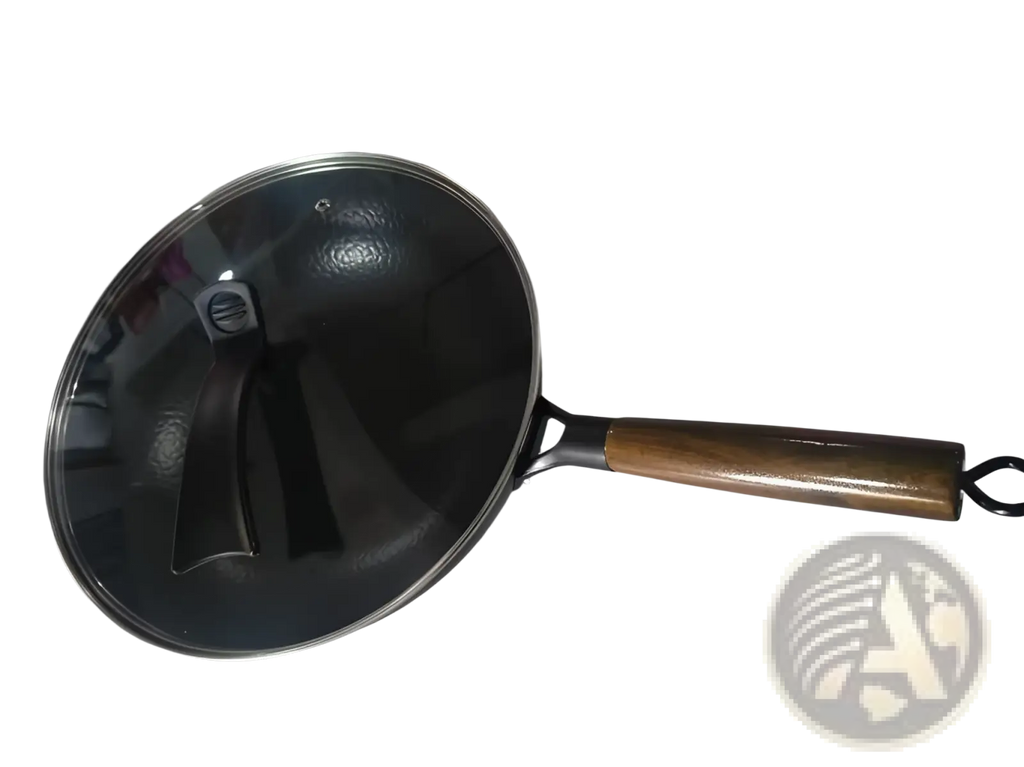 Handmade black iron wok with wooden handle, stainless steel rim, and clear glass lid for versatile cooking