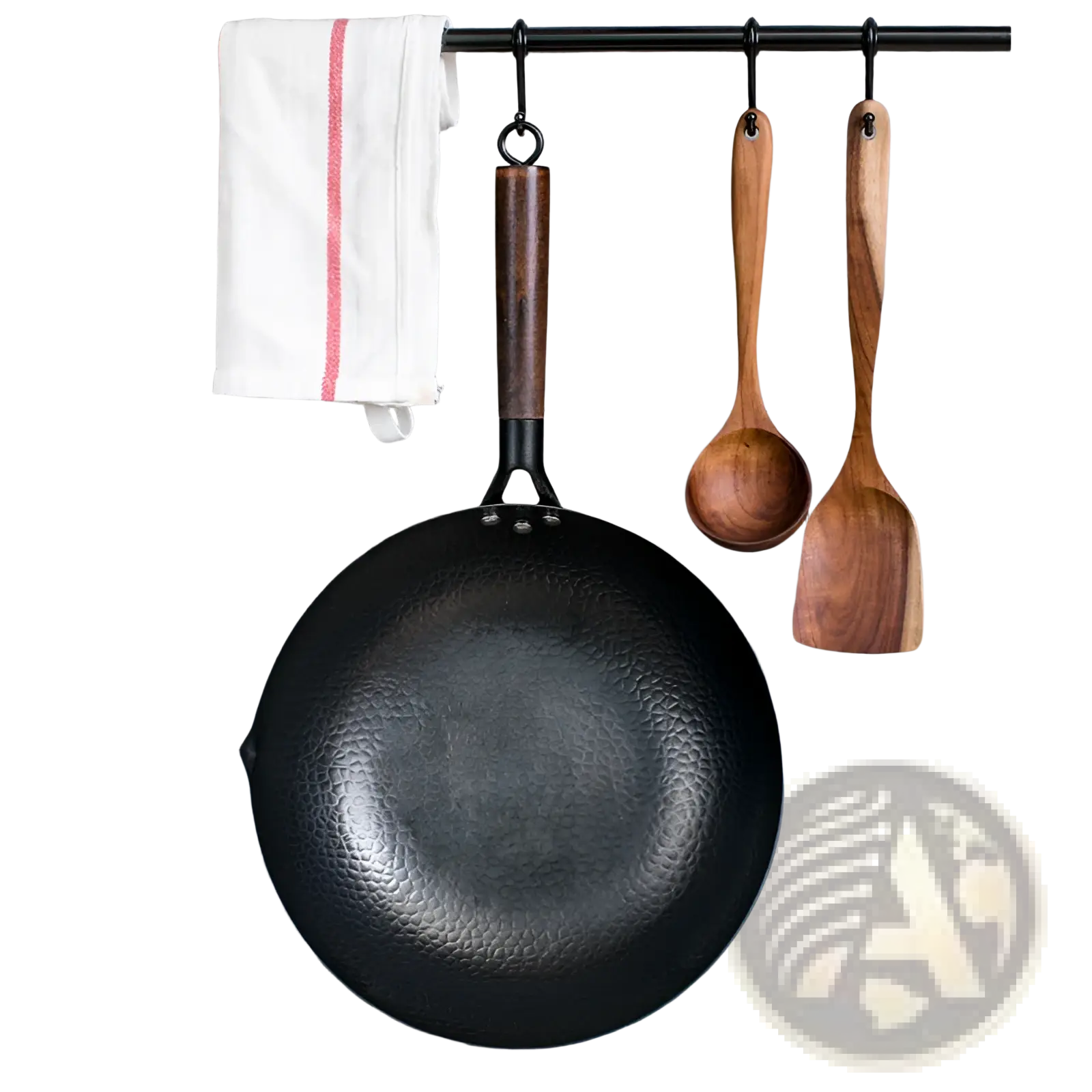 Handmade black hammered steel wok with dark wooden handle hanging on rack with glass lid nearby