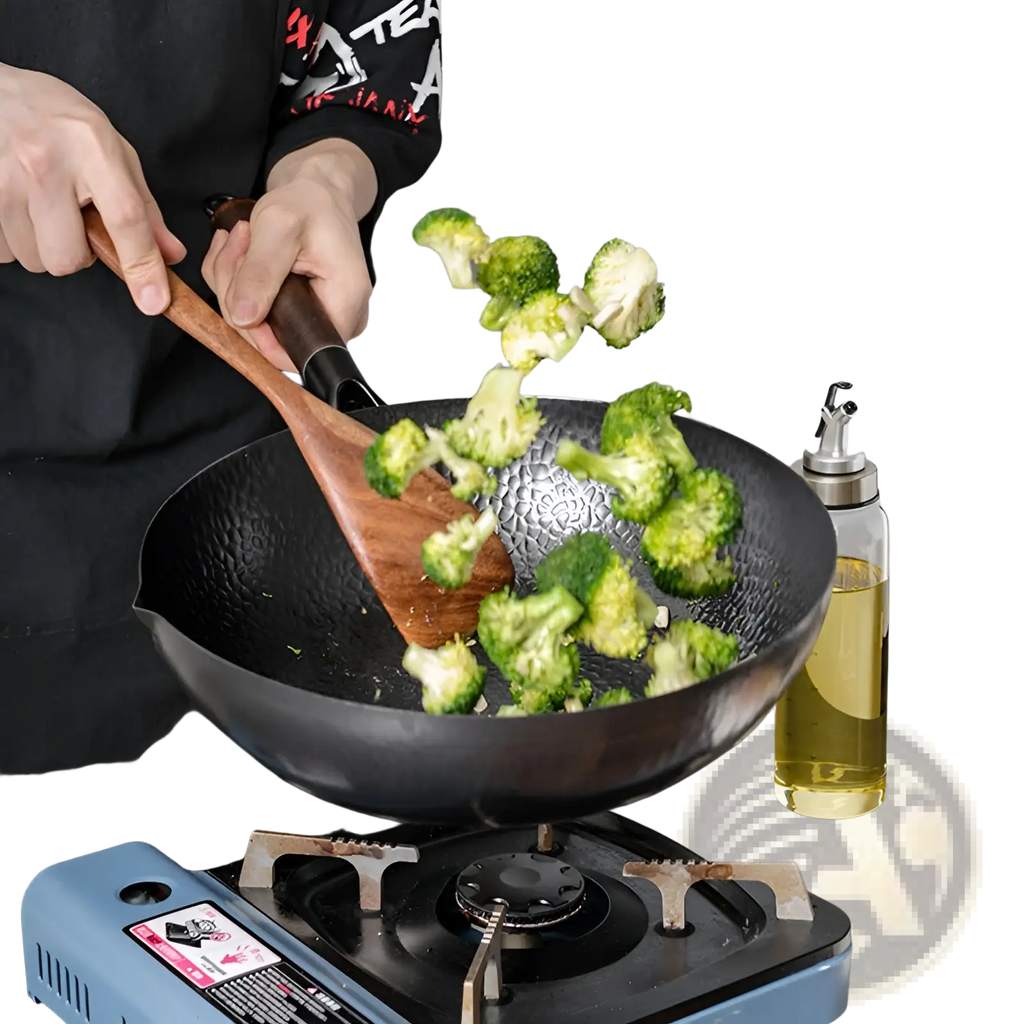 Handmade black textured iron wok with wooden handle and wooden spatula for versatile cooking use