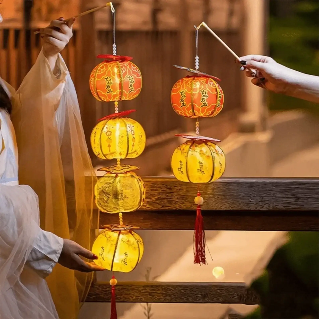 Handmade persimmon Chinese New Year lanterns with glowing orange and yellow paper, red tassels, and gold patterns hanging from wooden sticks