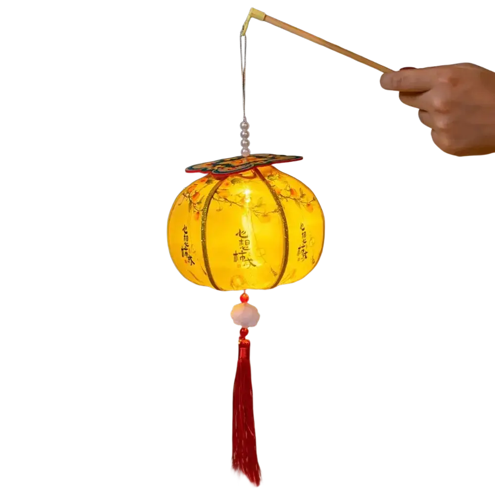 A glowing yellow handmade persimmon Chinese New Year lantern with floral designs, Chinese characters, red tassel, and pearls