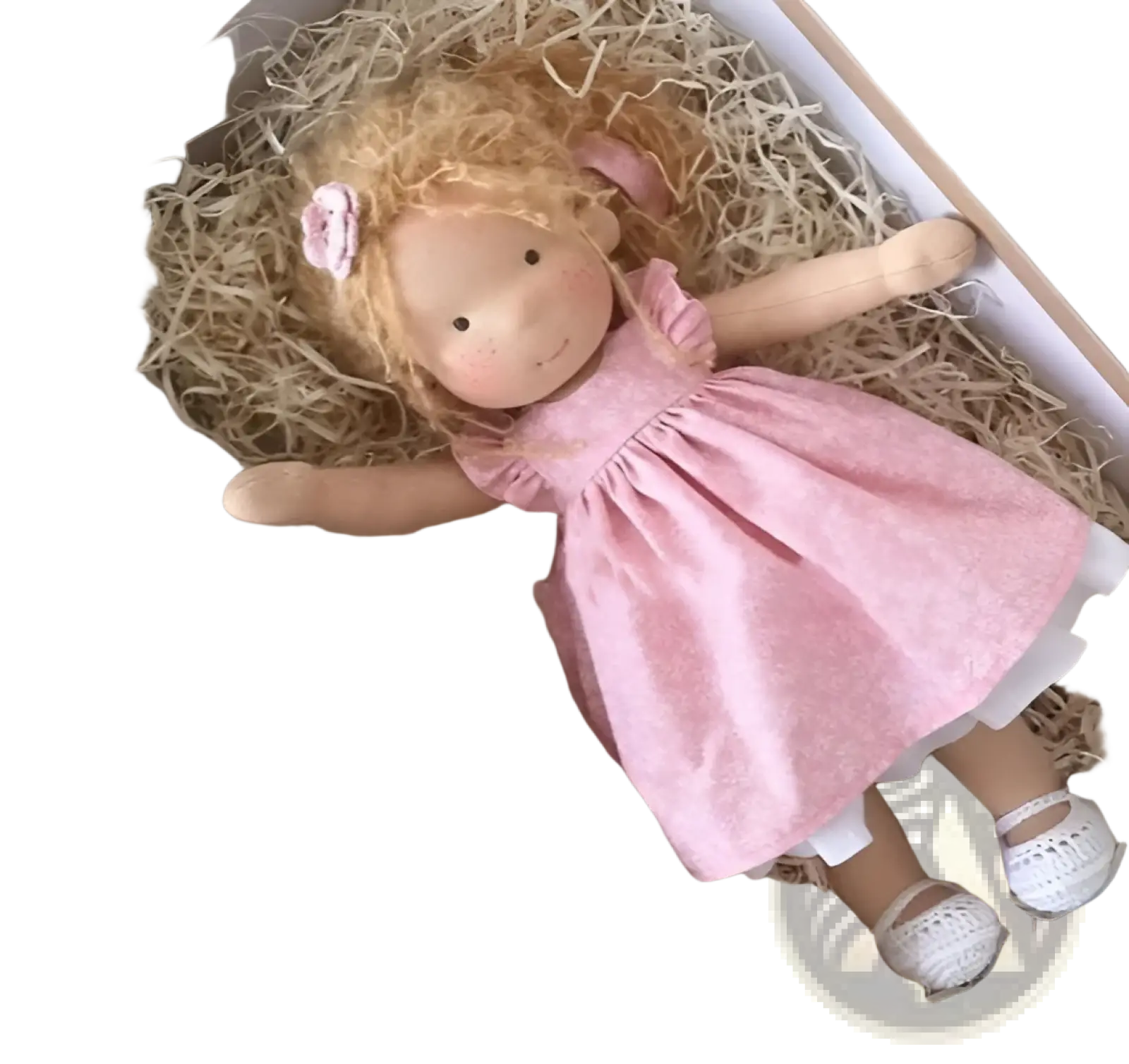 A soft handmade plush doll with golden curly hair and a pink dress nestled in straw inside a gift box