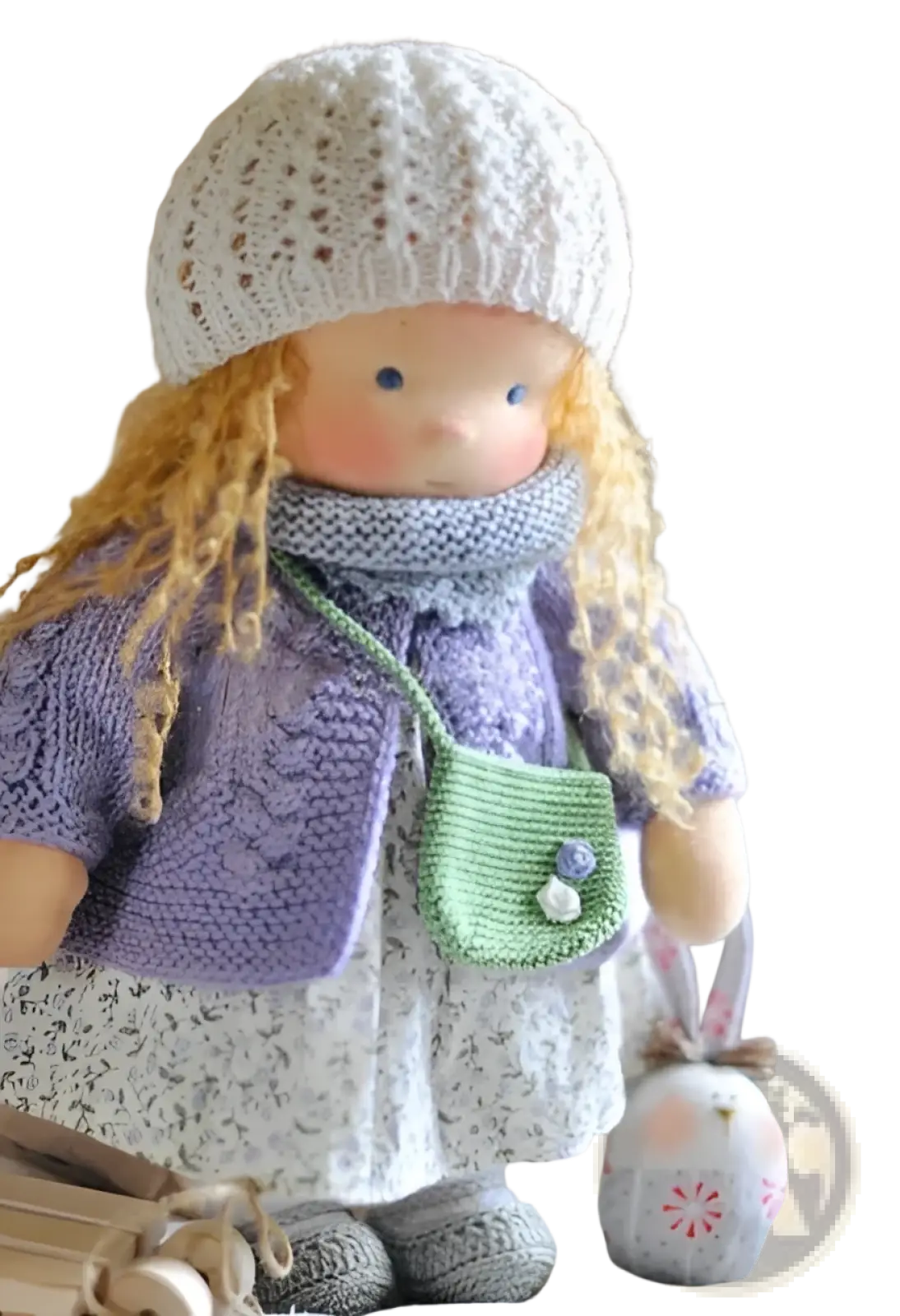 Handmade plush doll with golden curly hair wearing a white knitted hat and lavender cardigan over floral dress