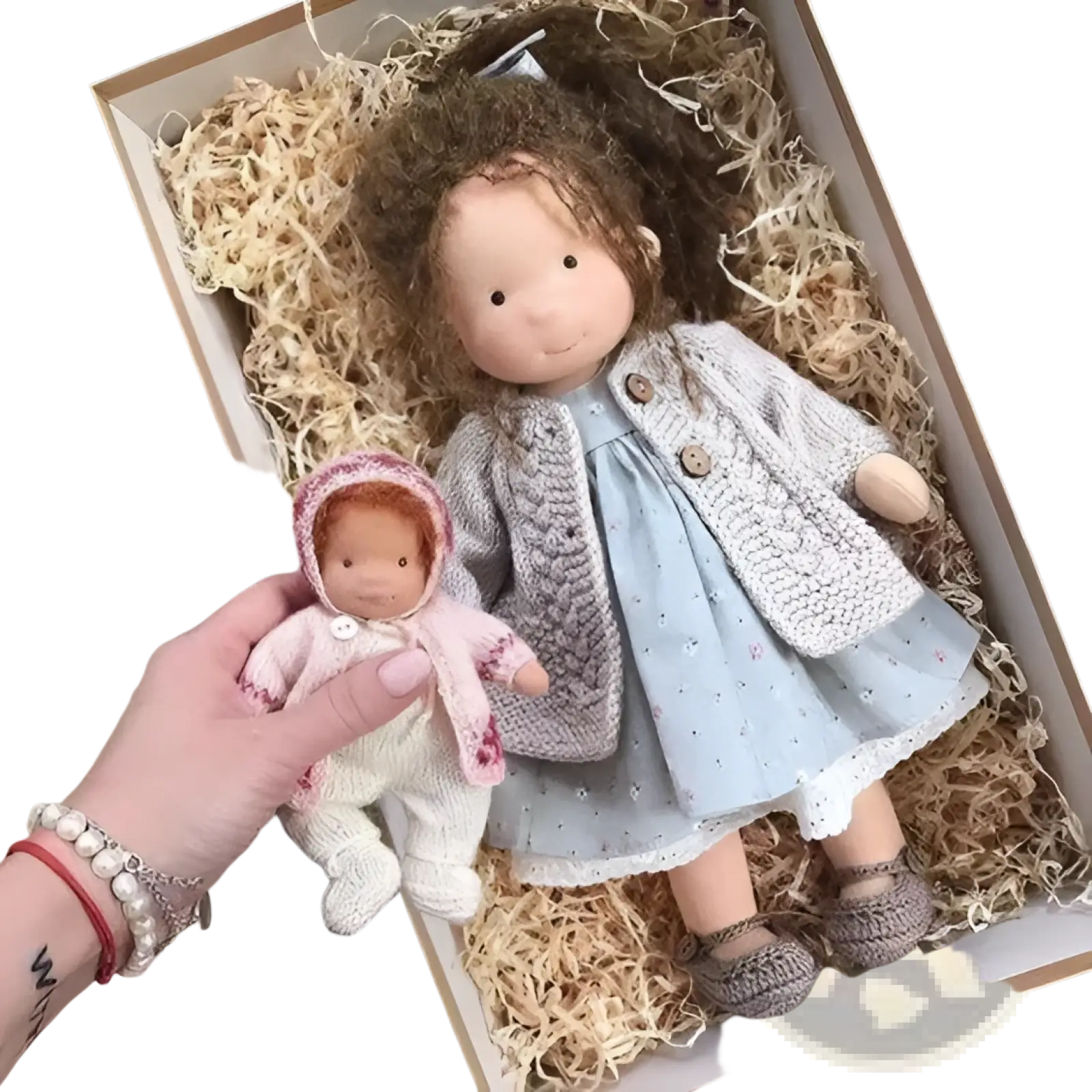 A hand holds a 30cm handmade plush doll with golden curly hair dressed in soft pink and white knitted floral attire
