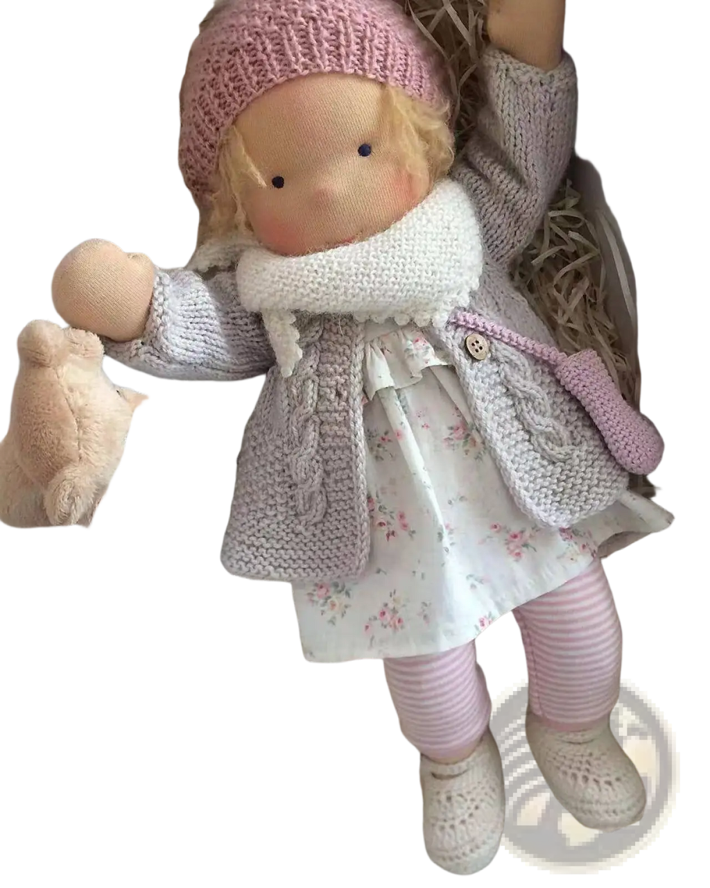 Handmade plush doll with golden curly hair wearing a pink knitted hat and gray cable-knit cardigan