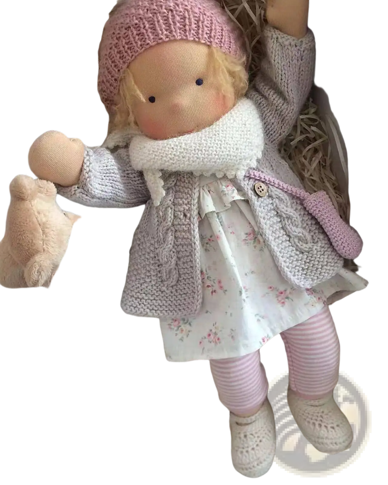 Handmade plush doll with golden curly hair wearing a pink knitted hat and gray cable-knit cardigan