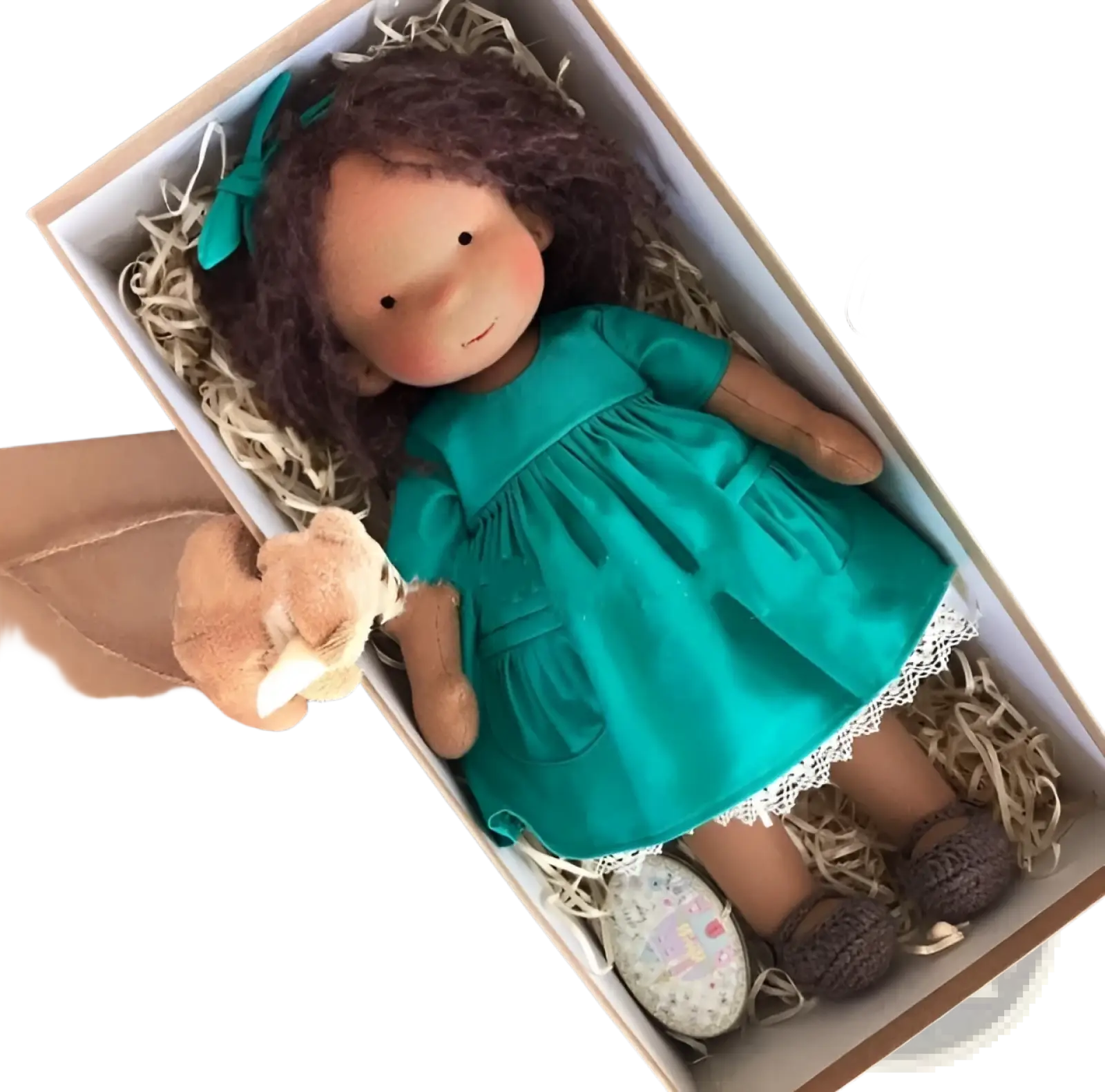 Handmade plush doll with golden curly brown hair wearing a teal dress nestled in straw inside its box