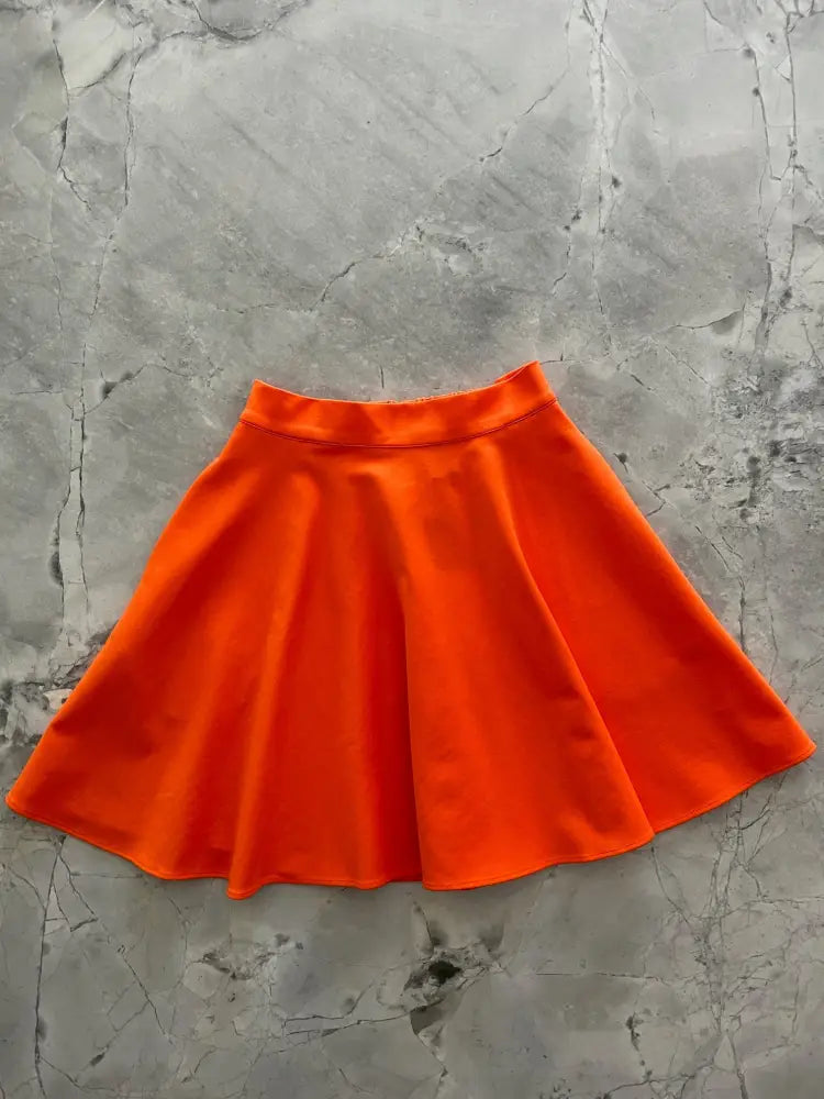 Harper orange pleated skater skirt with pockets made of vibrant smooth slightly shiny fabric and elastic waistband