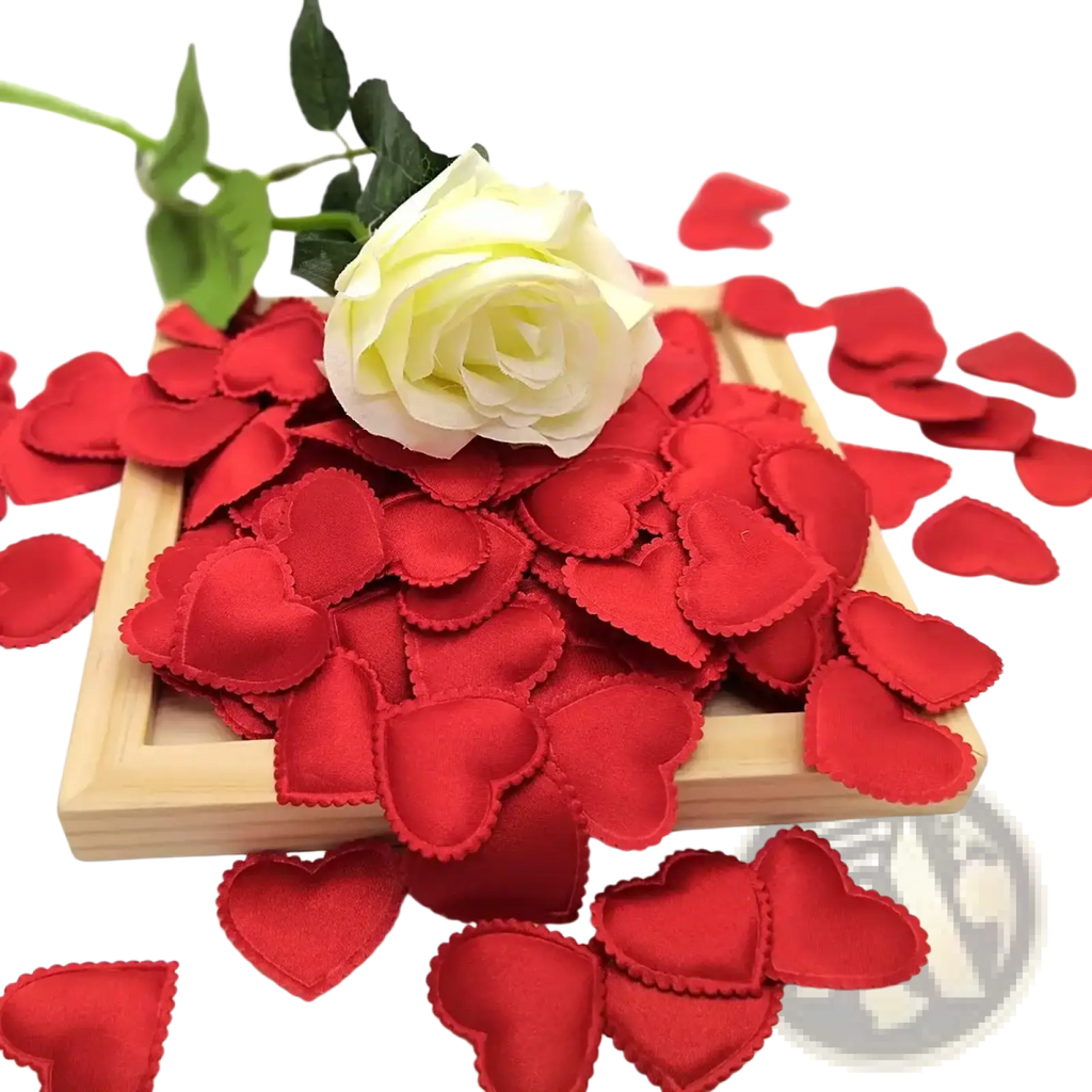 A vibrant red satin finish heart confetti scattered on a wooden tray with a white artificial rose for wedding decor