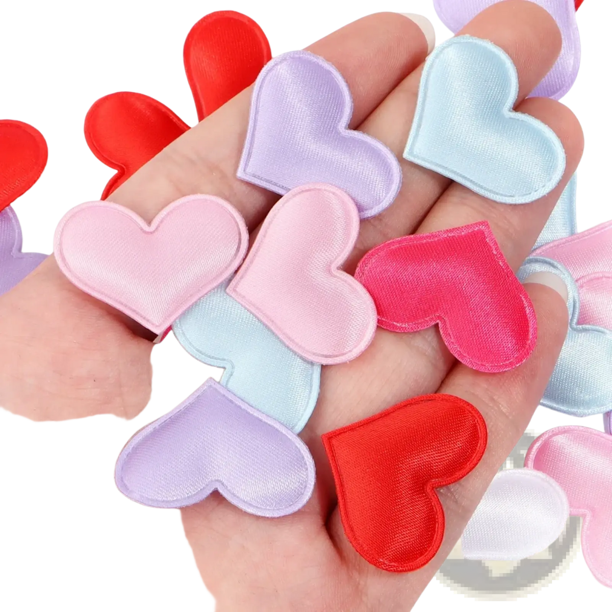 A hand holds heart confetti fabric table decor with satin finish heart-shaped patches in pastel and vibrant red hues
