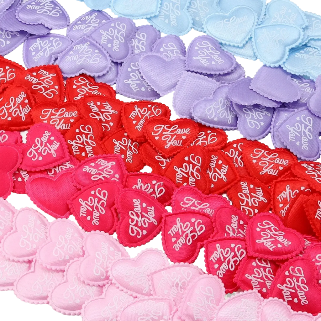 Heart confetti fabric table decor featuring heart-shaped patches in pink red purple and blue embroidered with i love you