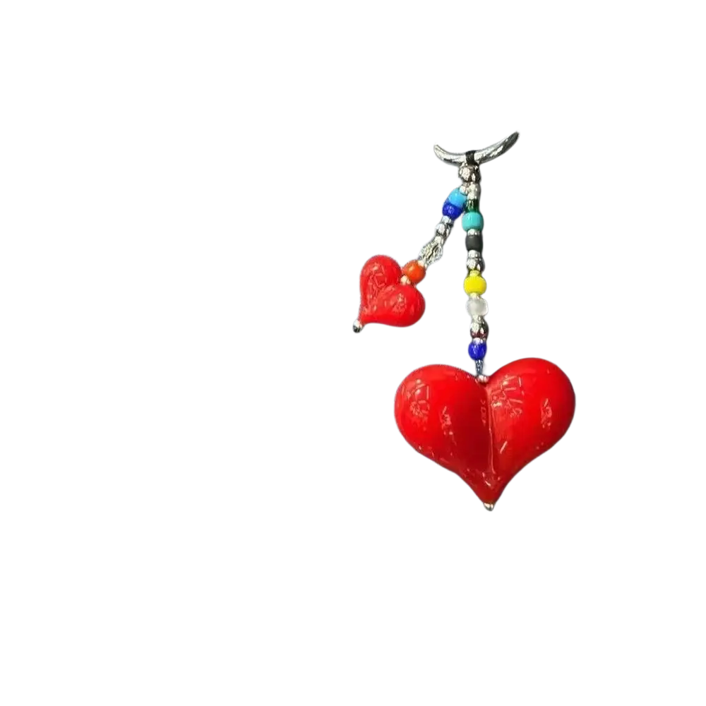 Vibrant red heart-shaped glass charm with colorful beaded chain hanging from denim handbag as bag charm