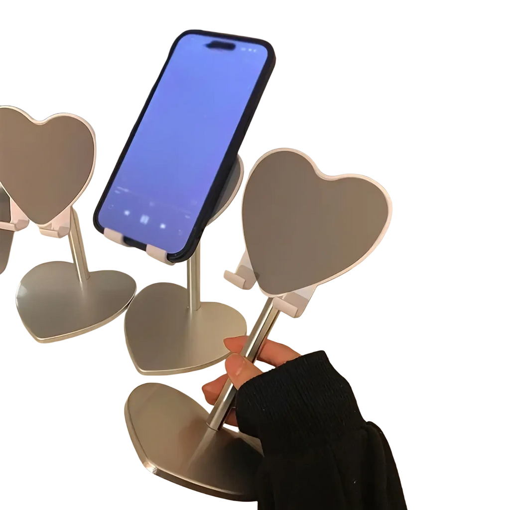 Silver heart shaped adjustable phone stand made of metal holding a smartphone on a desktop holder